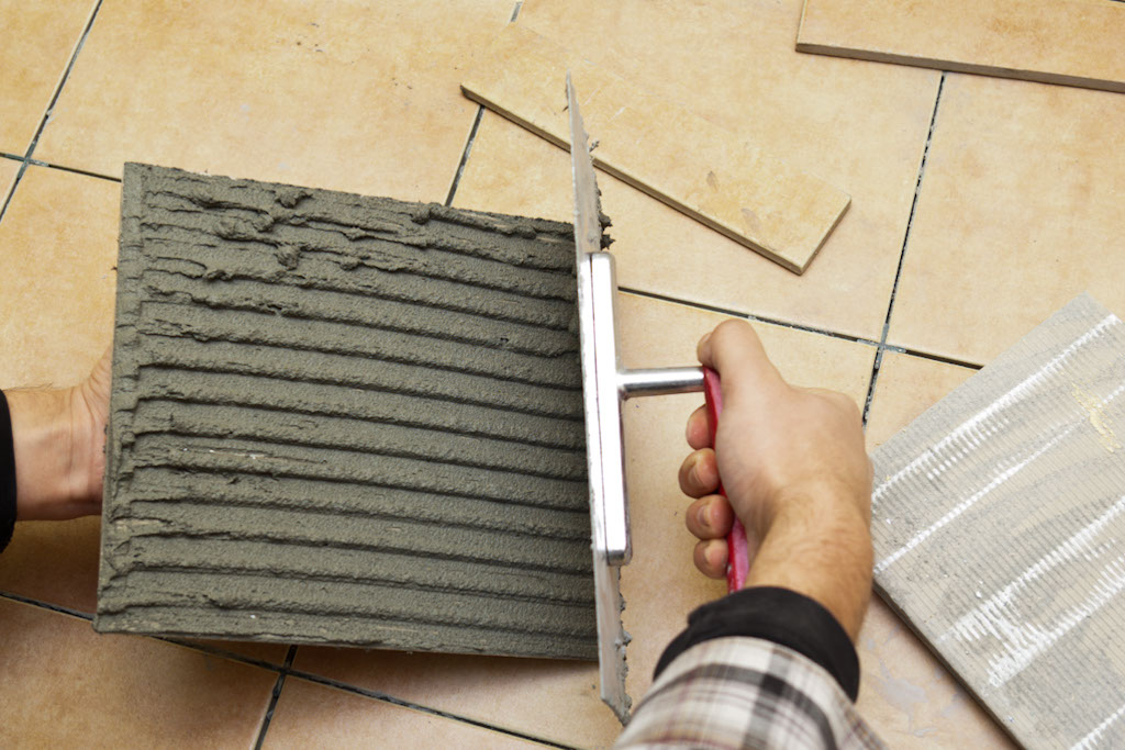 Spreading adhesive on tile